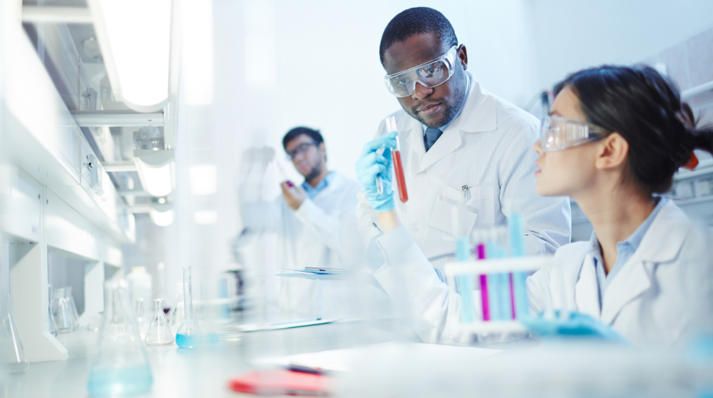 people working in a lab wearing lab coats and safety glasses