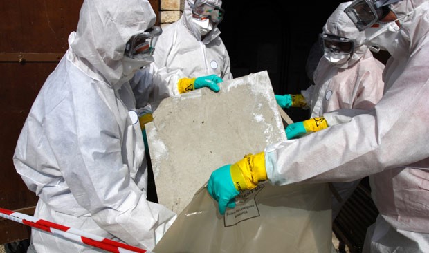 gowned up people placing asbestos waste into bag