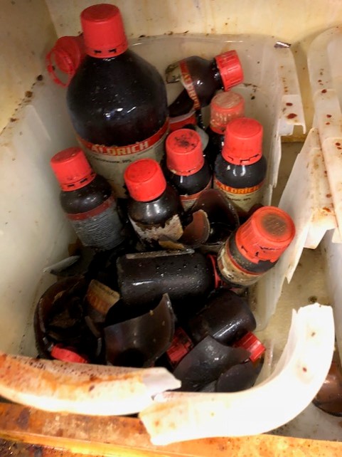 plastic container of amber chemical bottles, some broken