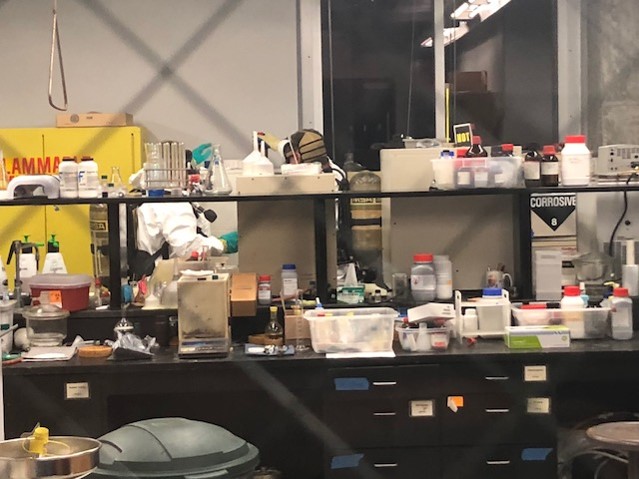 very cluttered lab bench with two men in the background