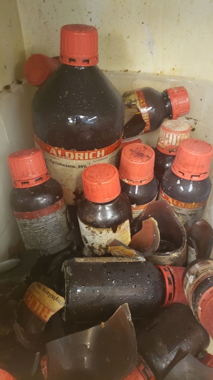 many amber chemical bottles, some broken, with crystals