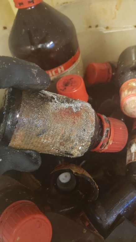 many amber chemical bottles, some broken, with crystals