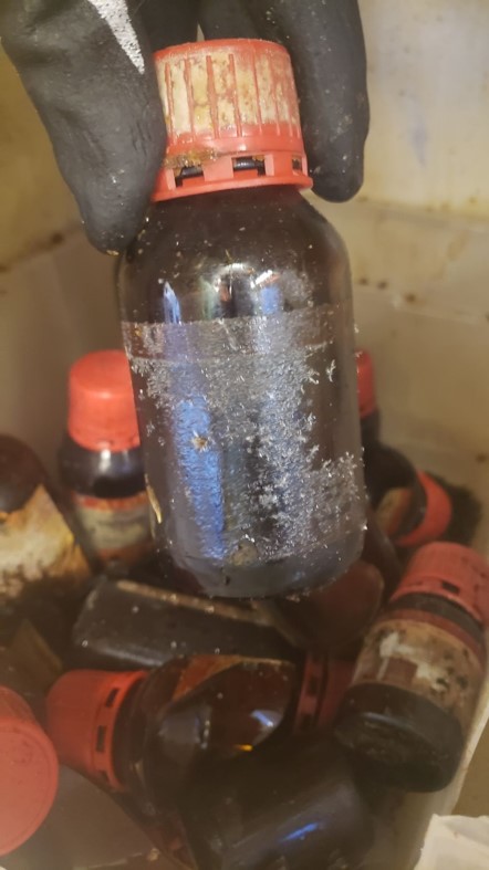 many amber chemical bottles, some broken, with crystals