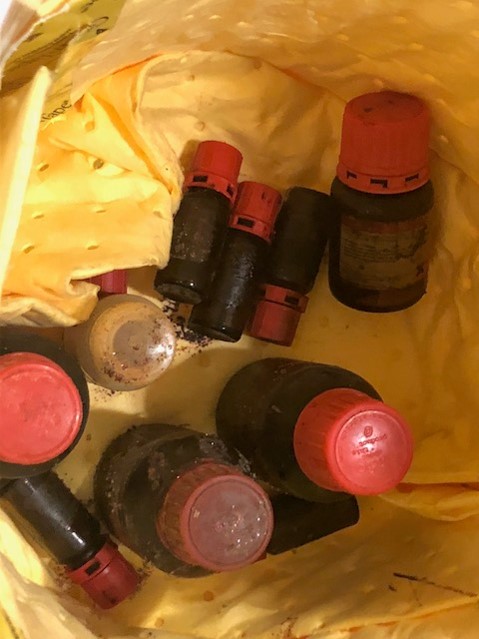 many amber chemical bottles, some broken, with crystals