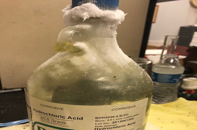 bottle of hydrochloric acid with white crystals near the cap